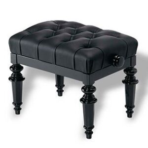 A black ottoman with tufted top and turned legs.